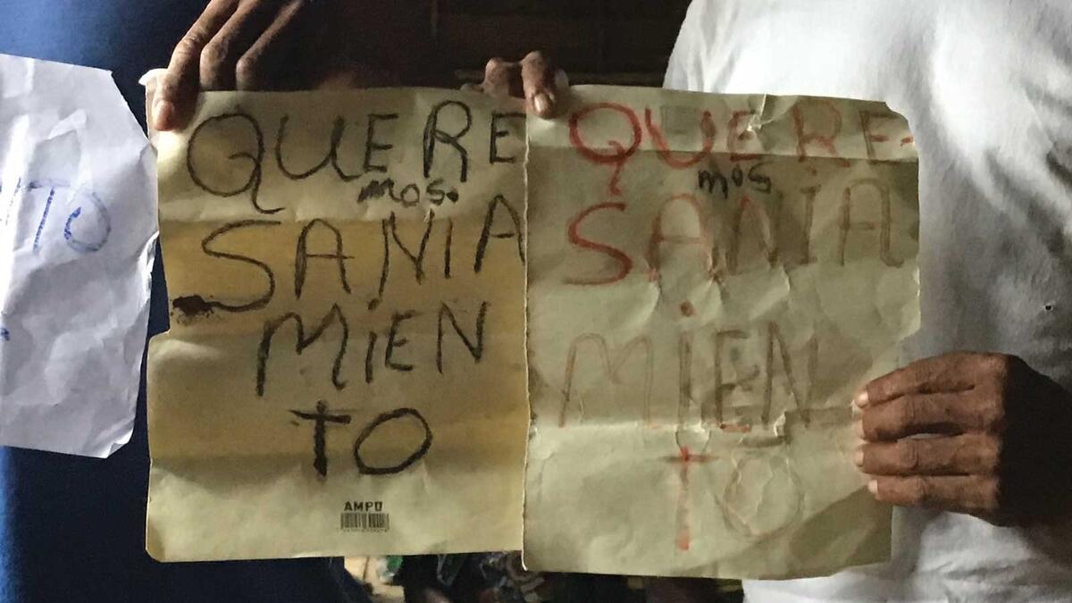 Miskitu villagers holding a sign demanding saneamiento.