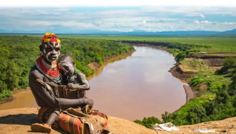 Kara parent and child sitting along the bank of the Omo River. Copyright Kelly Fogel