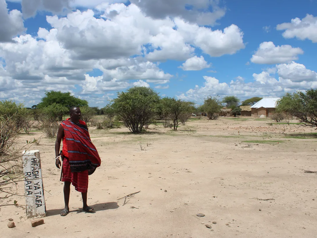 A Maasai pastoralist stands beside a beacon marking expansion of Ruaha National Park to consume his village and make communities trespassers in their own lands © The Oakland Institute