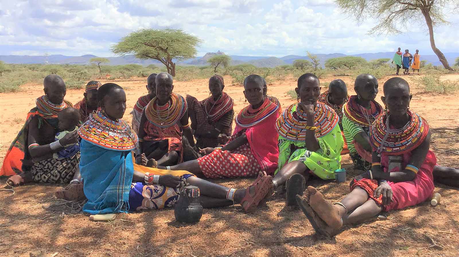 Maasai women in Kenya sitting underneath the shade of a tree 