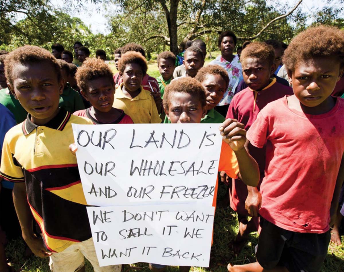 Children holding a sign &lquo;OUR LAND IS OUR WHOLESALE AND OUR FREEZER WE DON'T WANT TO SELL IT. WE WANT IT BACK.“