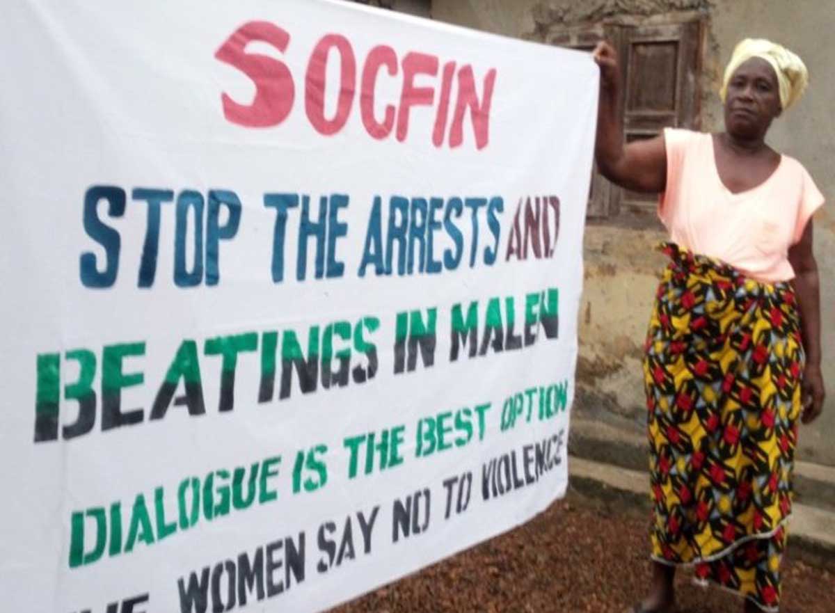 Women with banner: Socfin stop the arrests and beatings in Malen