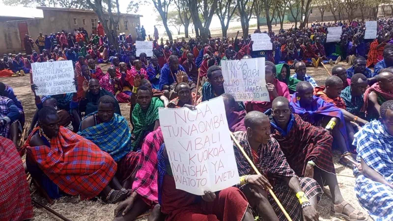 Seated protesters carrying signs with text